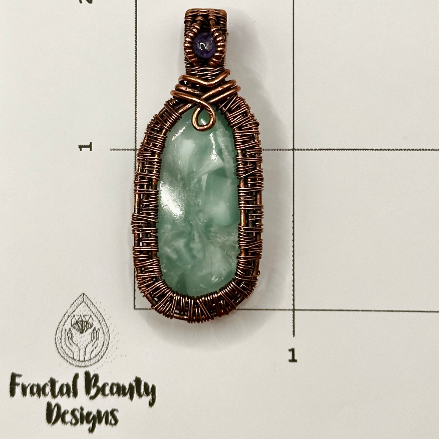 victoria stone with intricately woven antiqued copper frame accented with tanzanite facet on measuring grid