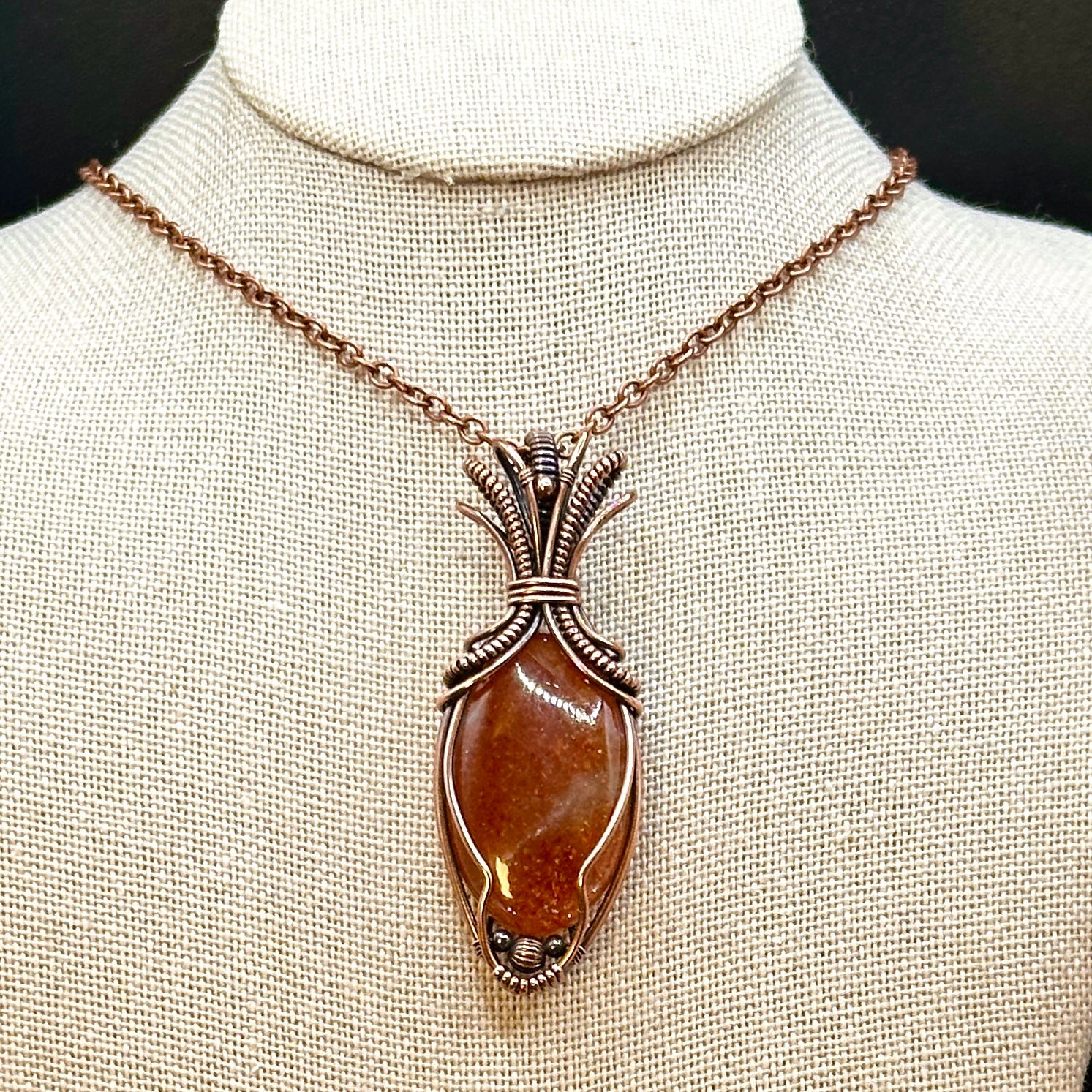 Oval Sunstone wrapped in copper in an "Art deco" design