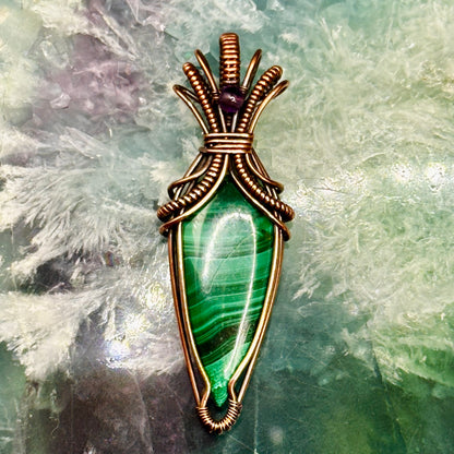 Tear shaped malachite stone wrapped in an "art deco" design with copper wire and accented with an amethyst bead
