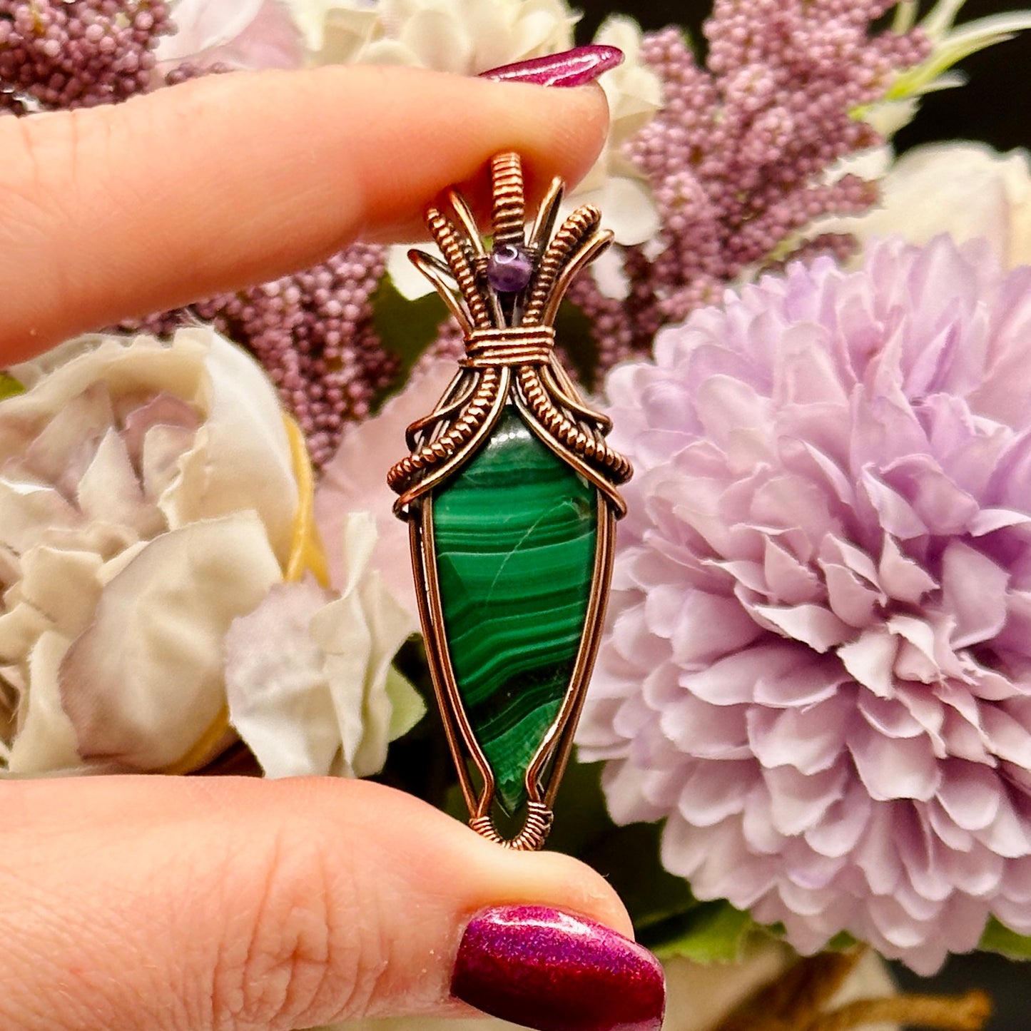 Tear shaped malachite stone wrapped in an "art deco" design with copper wire and accented with an amethyst bead