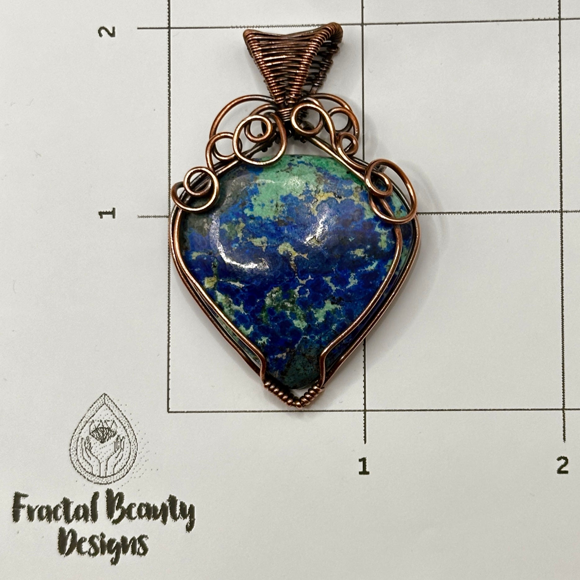 Azurite stone wrapped in antiqued copper on a measuring grid