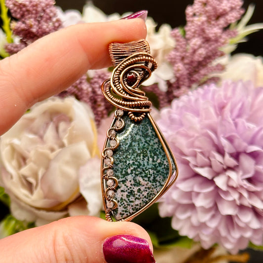 Triangle bloodstone pendant decorated with wavy wire interlaced with rose quartz beads and accented with a garnet bead