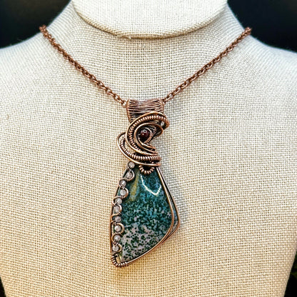 Triangle bloodstone pendant decorated with wavy wire interlaced with rose quartz beads and accented with a garnet bead