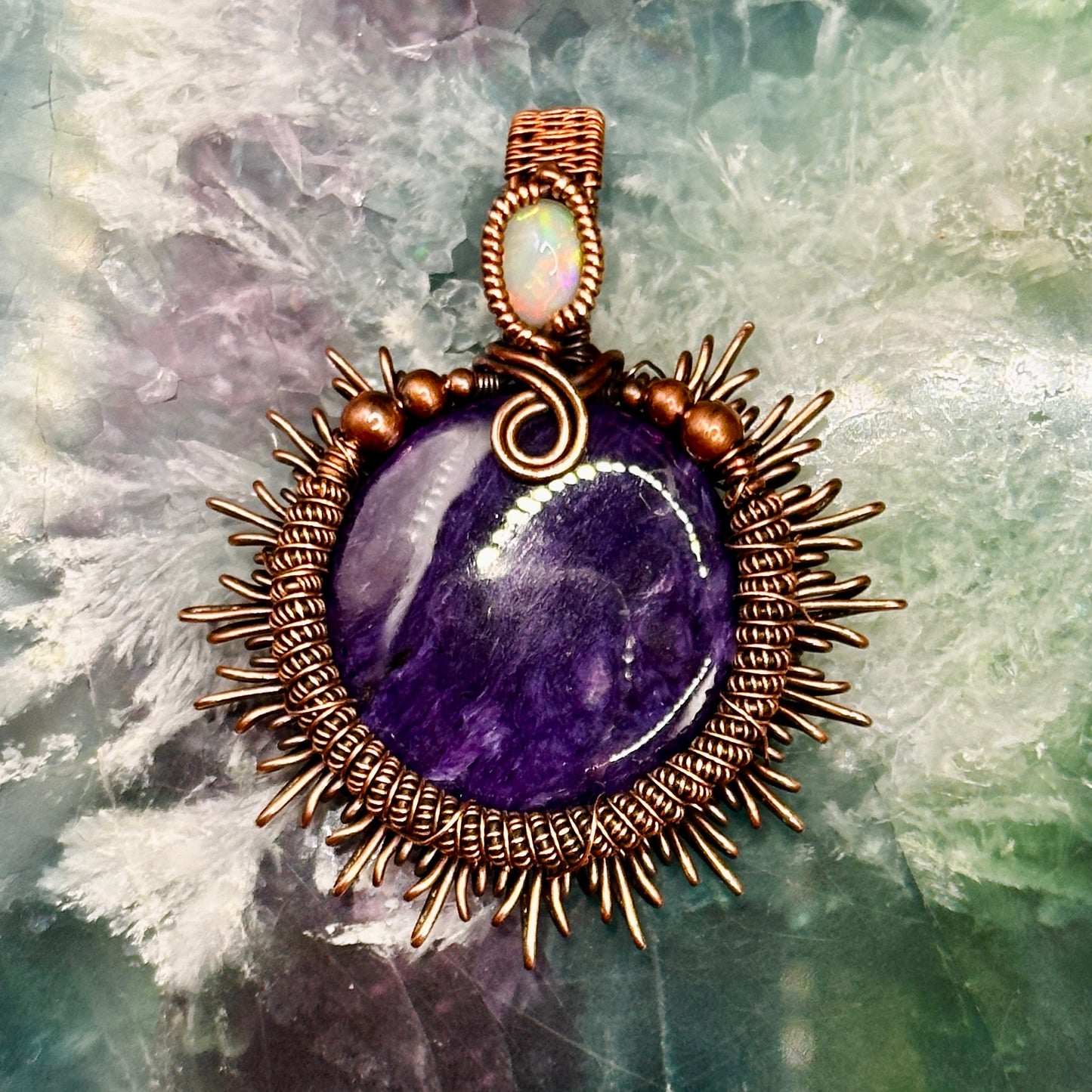 Charoite stone wrapped in sunburst design in antiqued copper accented with a double coil and ethiopian opal