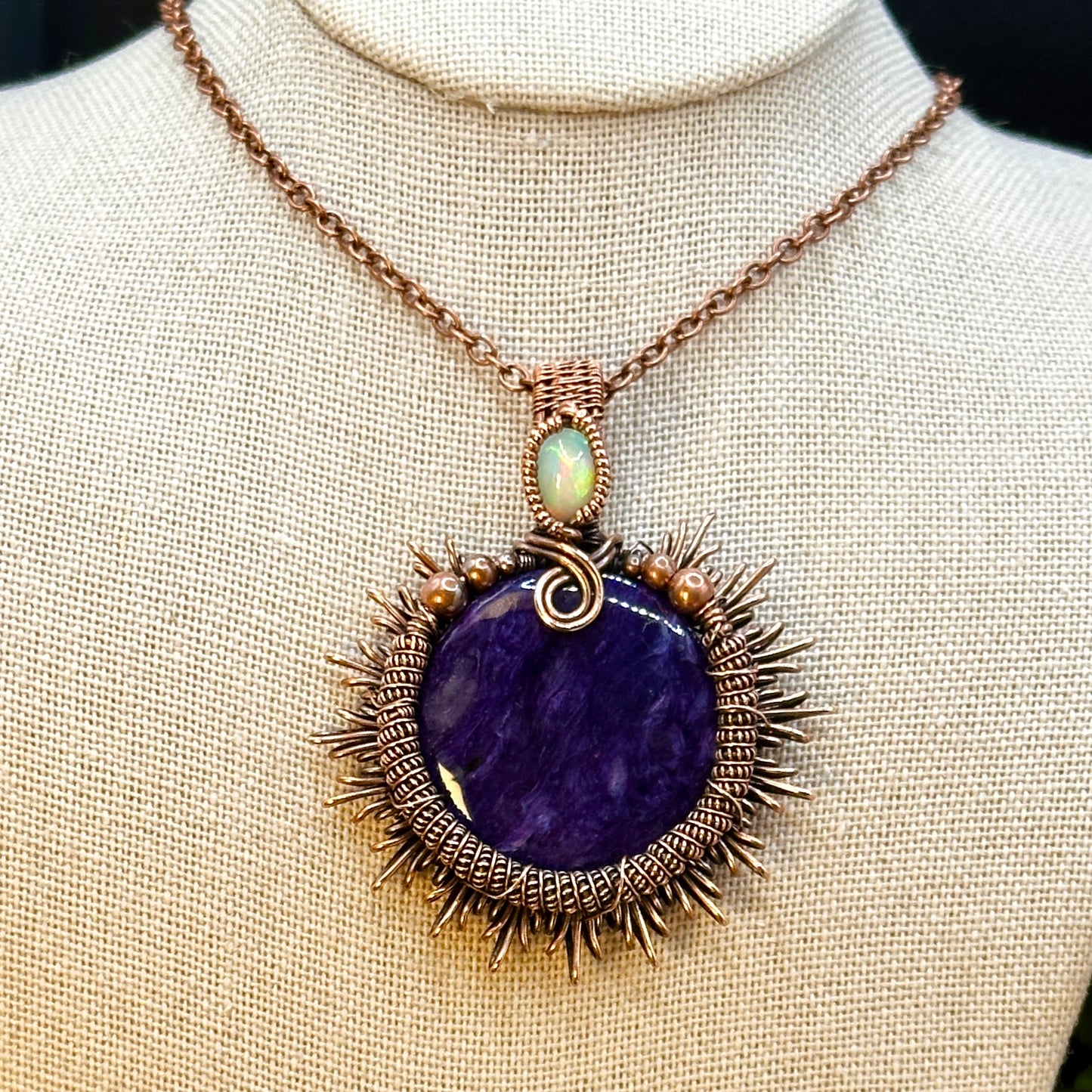 Charoite stone wrapped in sunburst design in antiqued copper accented with a double coil and ethiopian opal