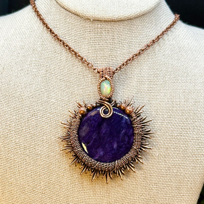 Charoite stone wrapped in sunburst design in antiqued copper accented with a double coil and ethiopian opal