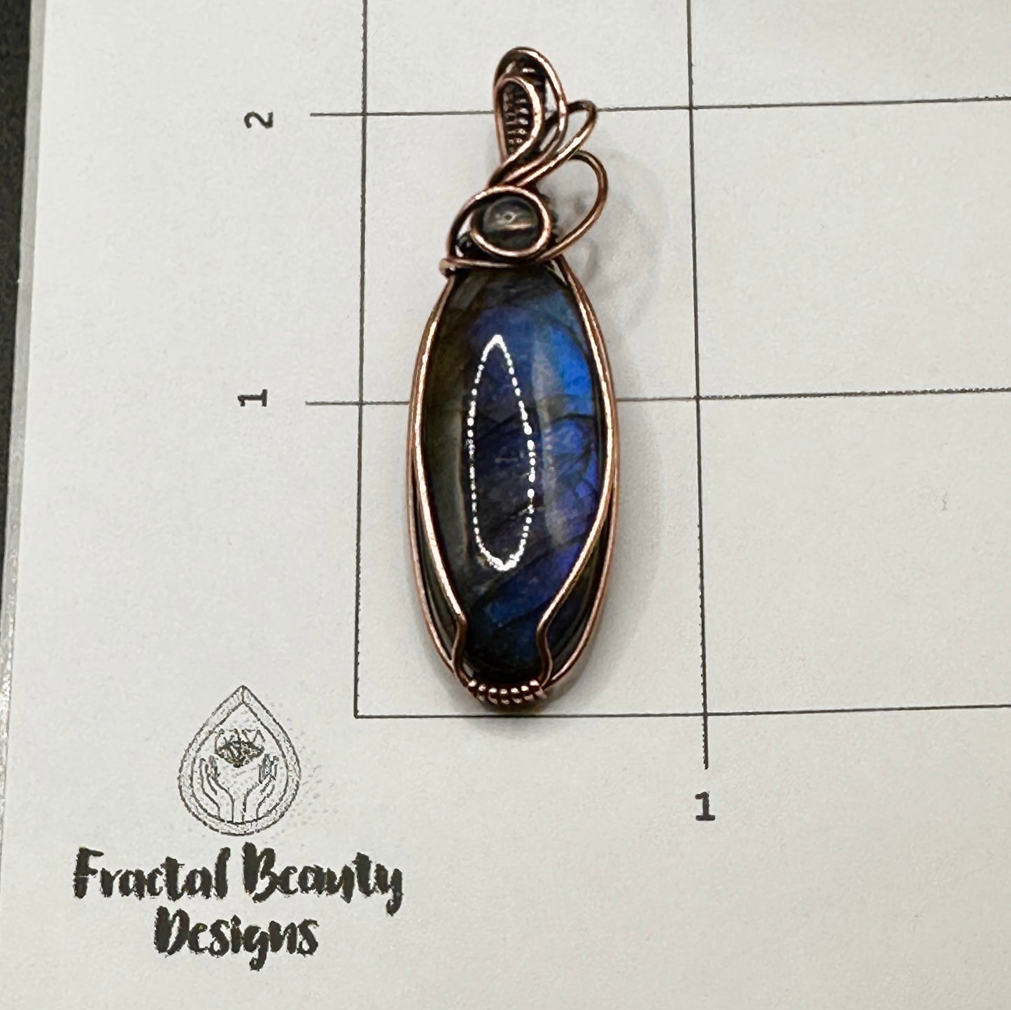 Oval blue labradorite with lab bead on measuring grid