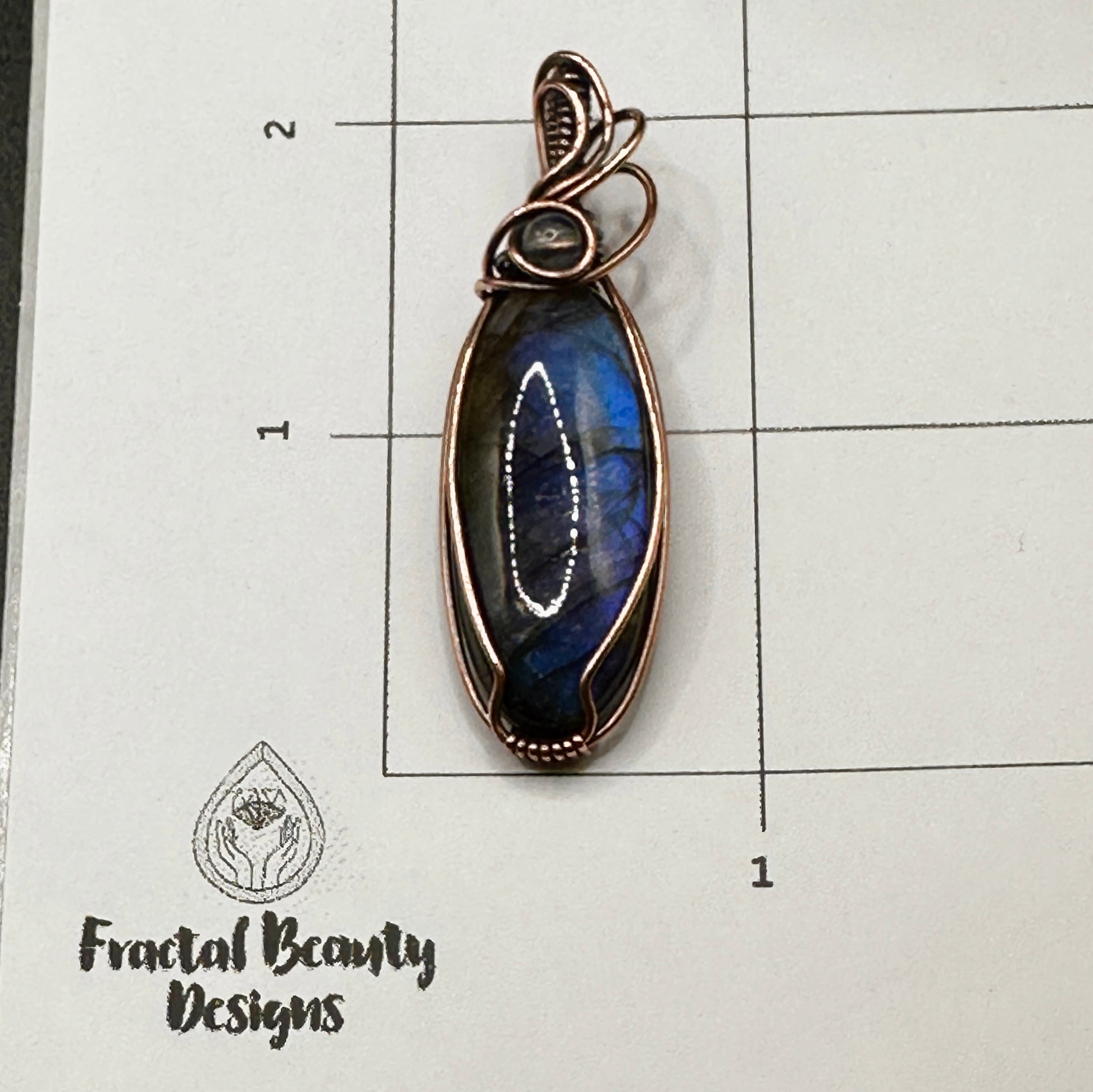Oval blue labradorite with lab bead on measuring grid