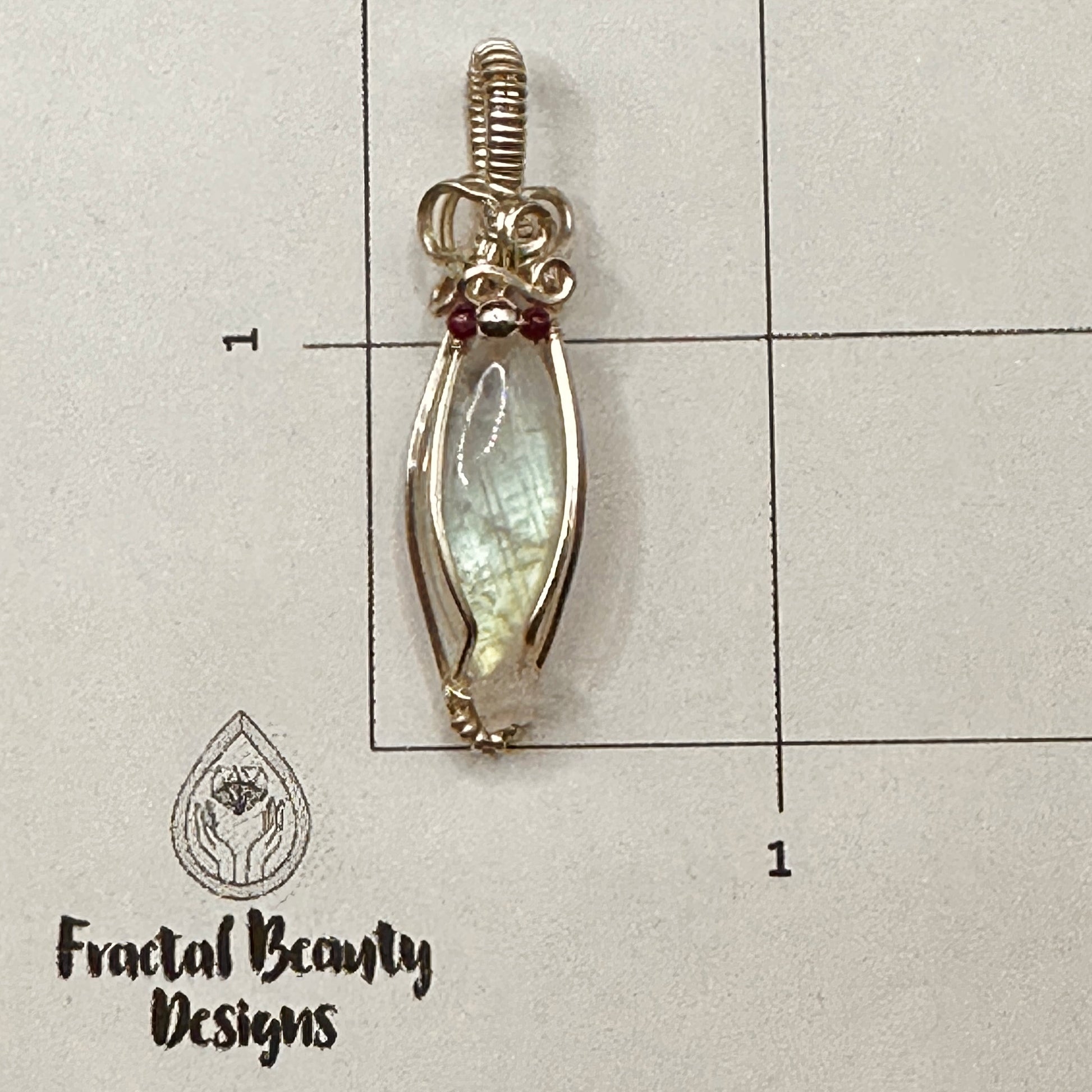 Marquis moonstone with garnet and silver beads and a rose quartz star, wrapped in silver plated copper wire on measuring grid
