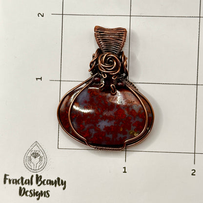 red plume moss agate stone wrapped in antiqued copper with rose and garnet accents on measuring grid