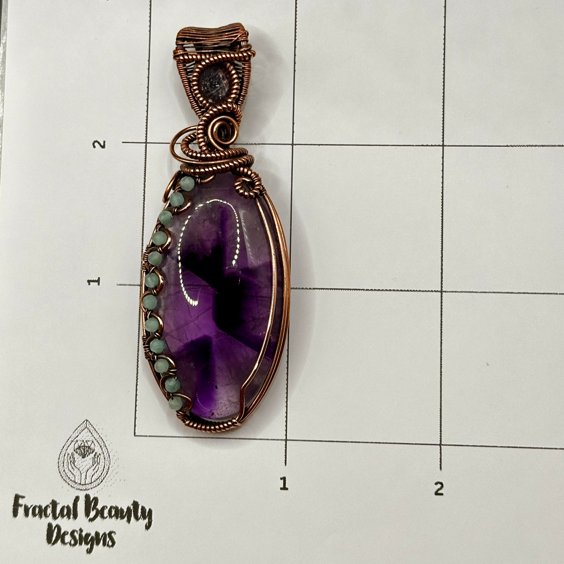 Trapiche Amethyst wrapped in antiqued copper w/ Amazonite beads & an Iolite Sunstone facet on measuring grid