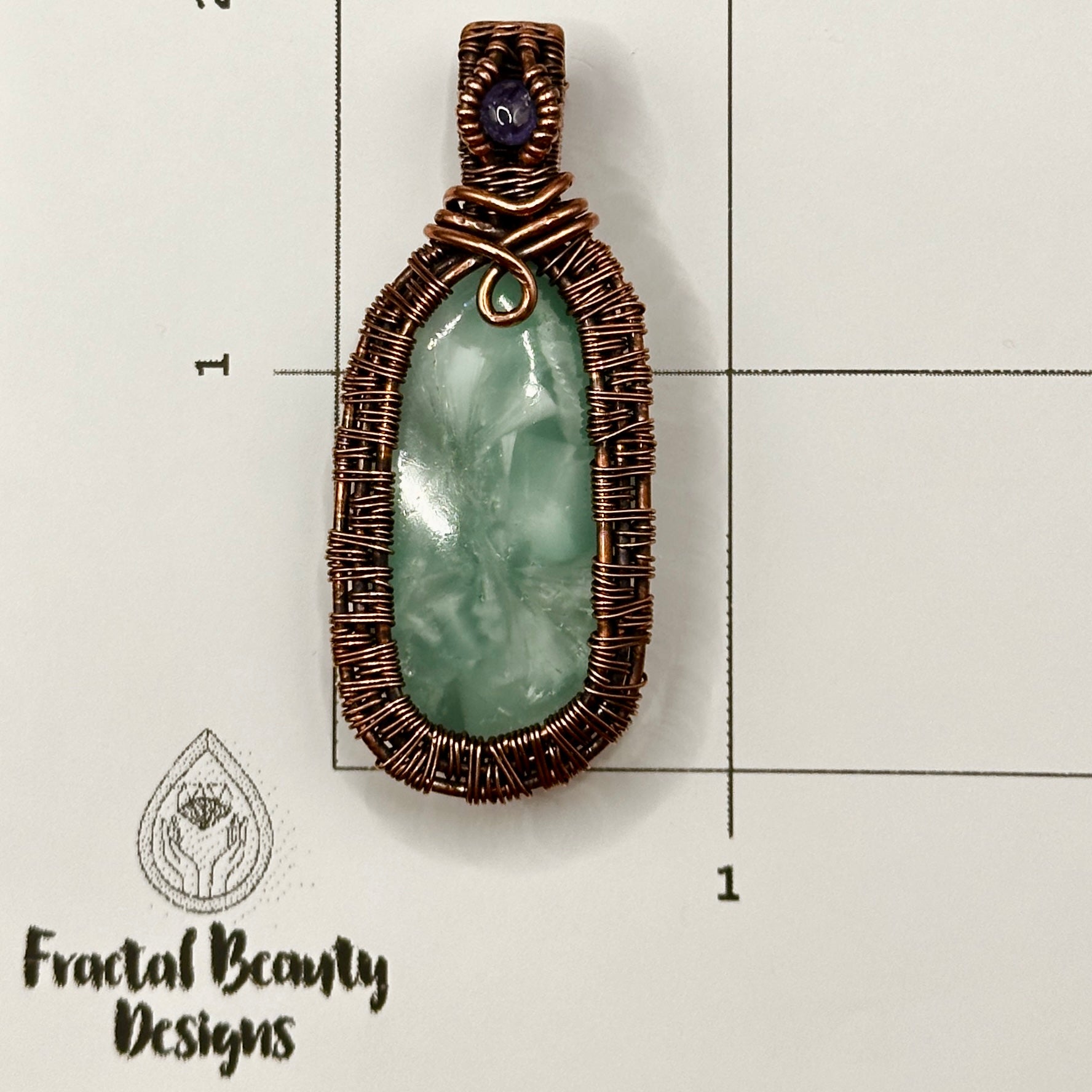 victoria stone with intricately woven antiqued copper frame accented with tanzanite facet on measuring grid