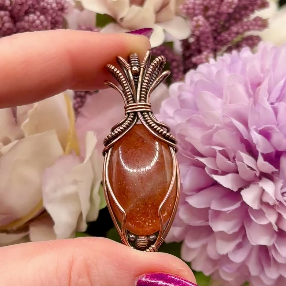 video of oval Sunstone wrapped in copper in an "Art deco" design to show the confetti flash